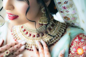 Close-up of a bride's face, highlighting intricate gold and red jewelry.