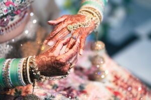 Close-up of a bride's hands adorned with intricate mehndi and sparkling jewelry.
