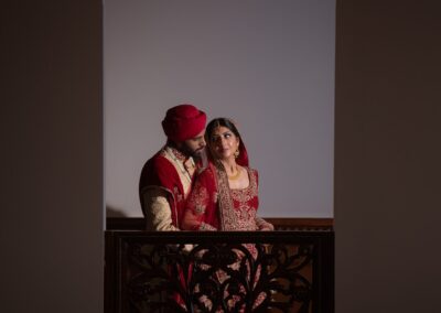 Couple posing in traditional attire framed by ornate arched window design.
