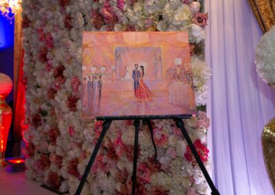 Painting of bride and groom displayed against floral backdrop at wedding venue.