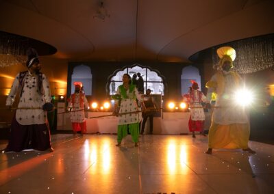 Bhangra dancers performing in vibrant costumes under bright stage lighting.