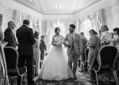 Bride and groom walking down aisle together inside elegant wedding hall.